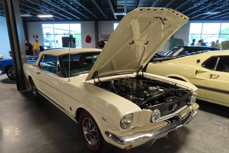 Front profile of white Mustang with hood open parked in garage