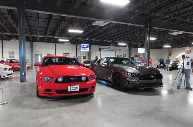 Fronts of a red and black Mustangs parked in garage