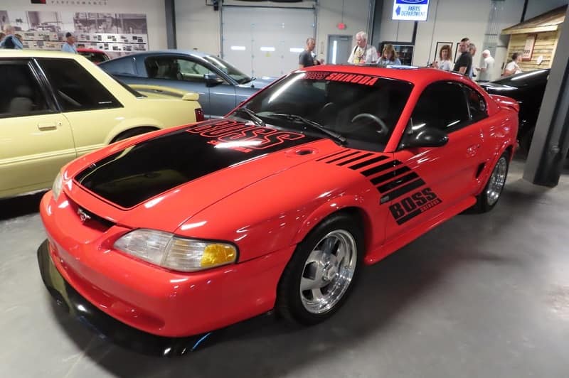 Front profile of red Mustang Boss with black hood parked in garage