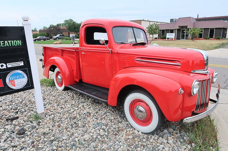 Front profile of red classic Ford pickup on side of road