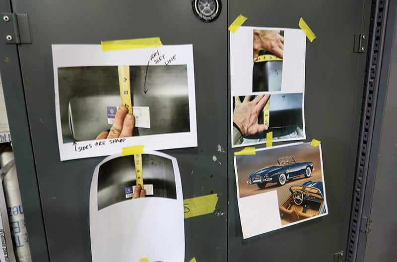 Papers taped to a cabinet with pictures of cars and measuring tape on them