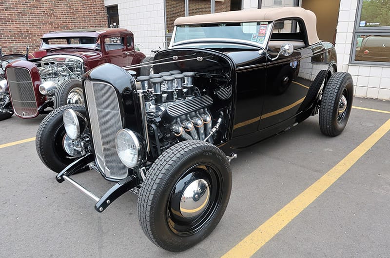 Front profile of a black classic Ford in parking lot