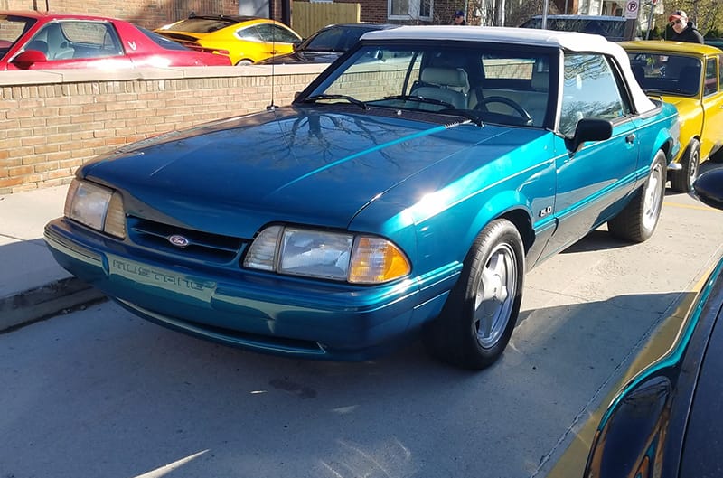 Front of a teal blue Mustang in parking lot