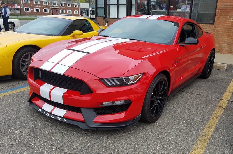 Front of a red Shelby Mustang with white stripes in parking lot
