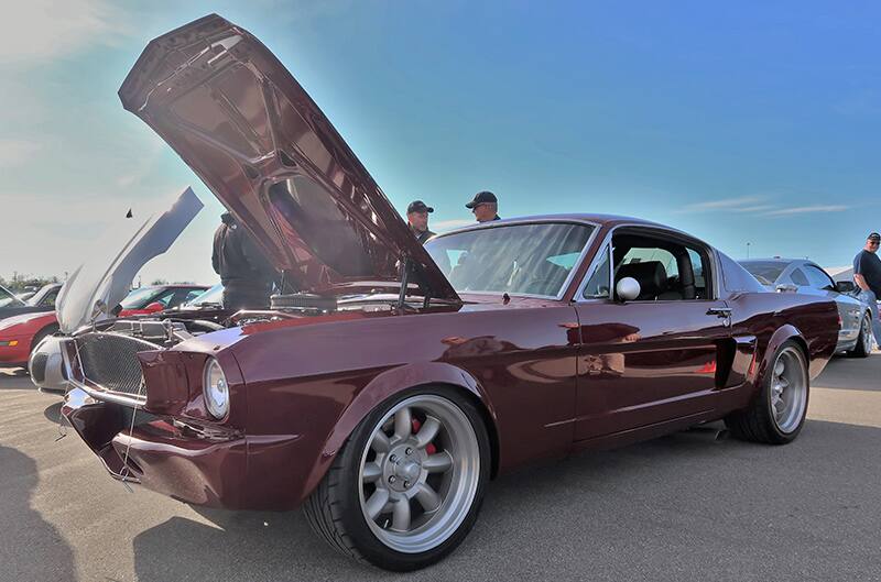 A front side view of a classic maroon Mustang on display