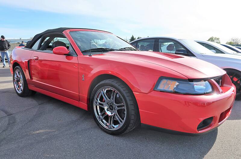 A front side view of a red Mustang convertible on display