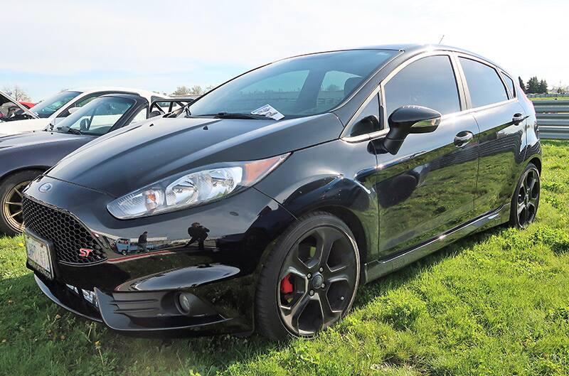 A front side view of a black Ford compact car on display