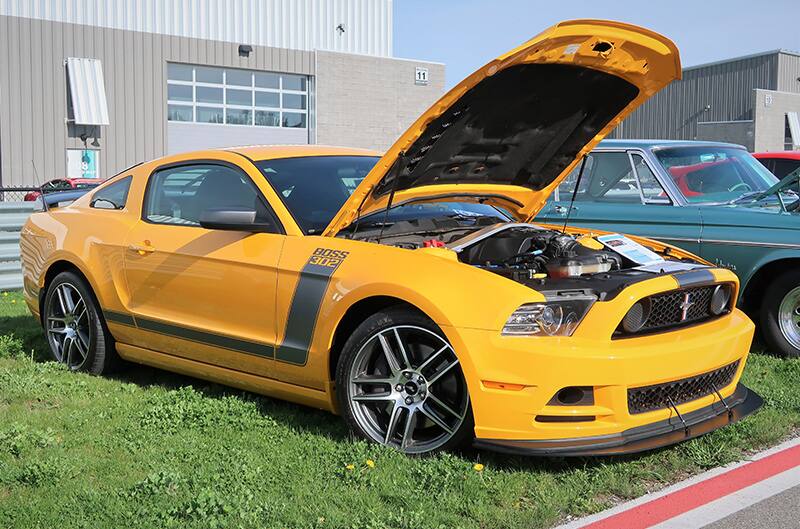 A yellow and black Mustang on display with the hood up