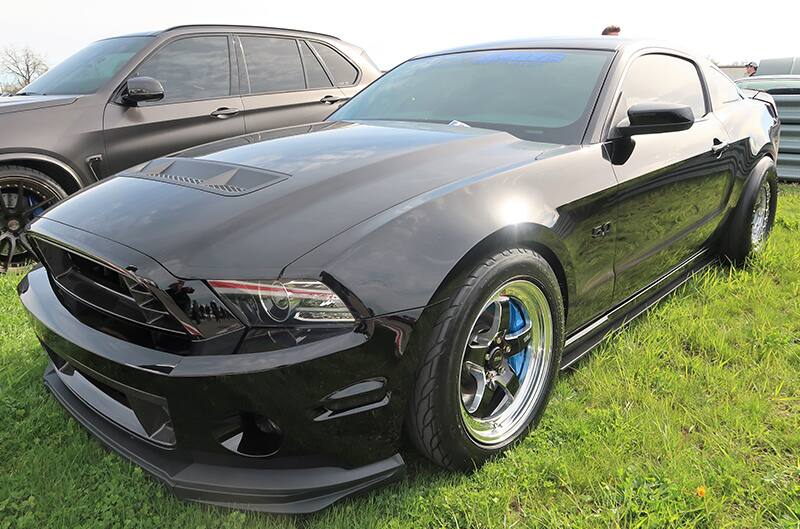 A closeup of a front side view of a black Mustang on display