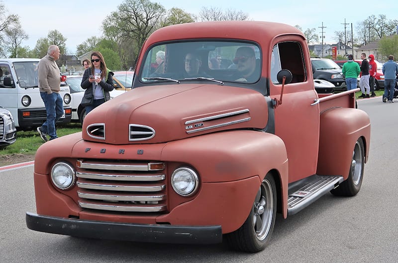 A classic red Ford truck being driven down the road