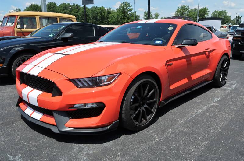 Front profile of a red Mustang with white stripes in the parking lot