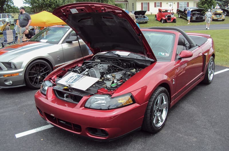 Front of a red Shelby Mustang with hood open in parking lot