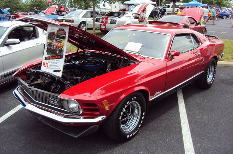 Front profile of a red Mach 1 with hood open in the parking lot