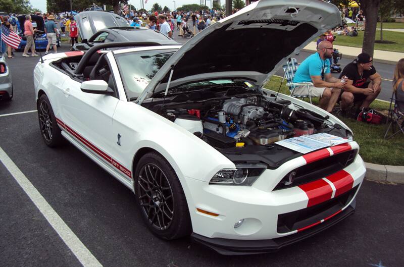 Front of a white Shelby with red stripes on open hood in the parking lot