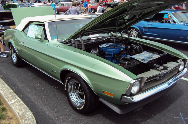 Front profile of a green Mustang with hood and trunk open in the parking lot