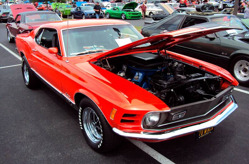 Front profile of a red Mustang with hood open in the parking lot