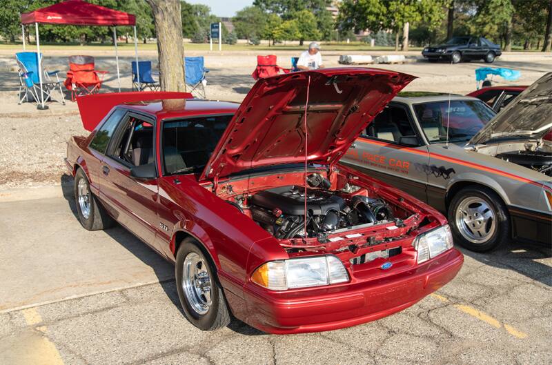 Front of a red Mustang with hood open in the parking lot