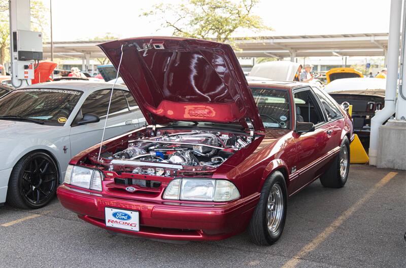 Front of a red Mustang with hood open in the parking lot