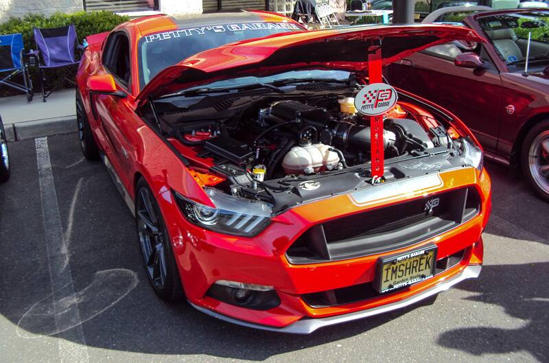 Front of a red Mustang with hood open in parking lot