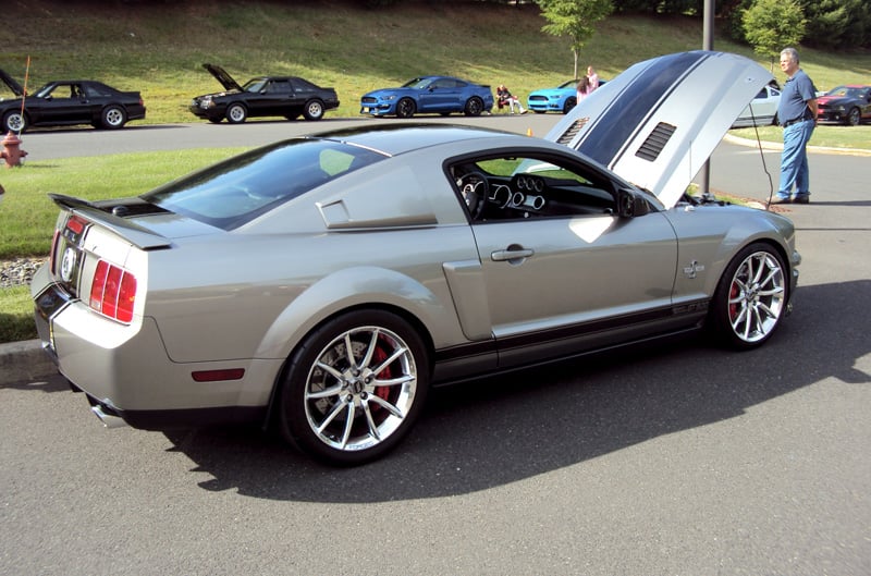 Profile of gray Shelby Mustang with black stripes on open hood in parking lot