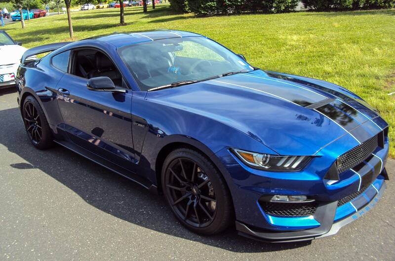 Front profile of a blue Shelby Mustang with black stripes in parking lot