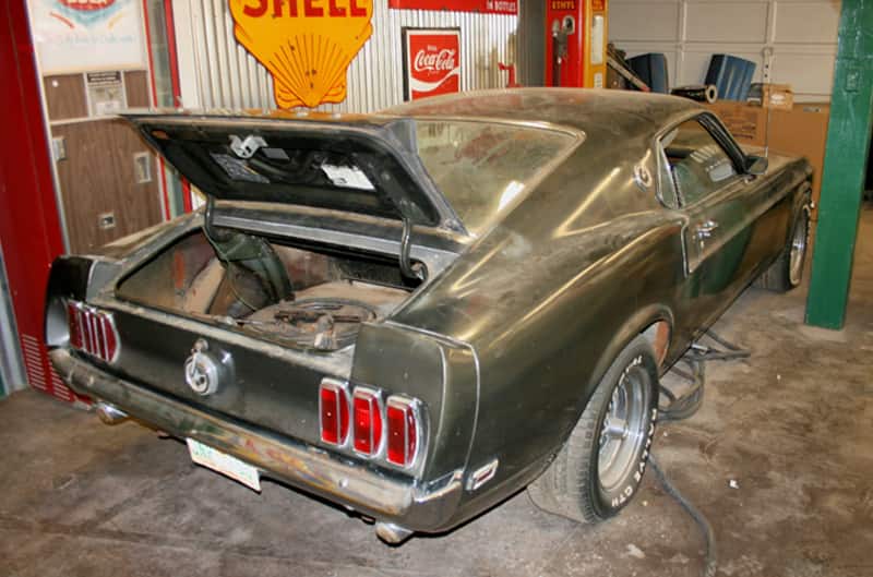 Rear of dusted black Mustang Boss 429 with trunk open in garage