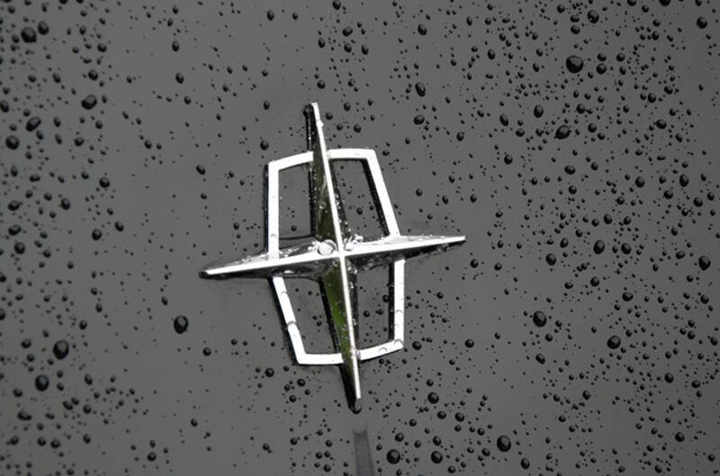 A closeup of the side of a black vehicle covered in rain droplets