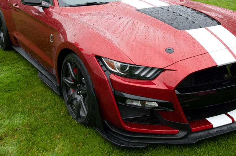 A closeup of the front side of a red Mustang