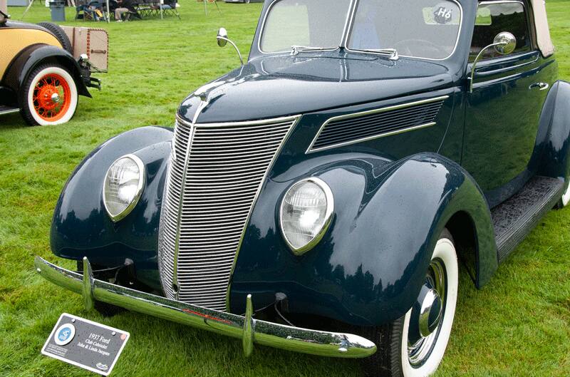 A front side view of a classic 1937 Ford vehicle on display