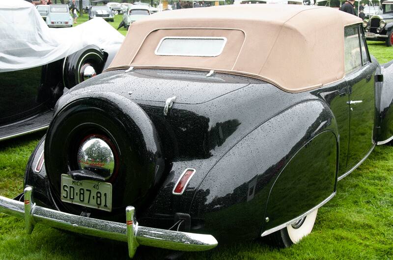 A rear side view of a classic black vehicle on display