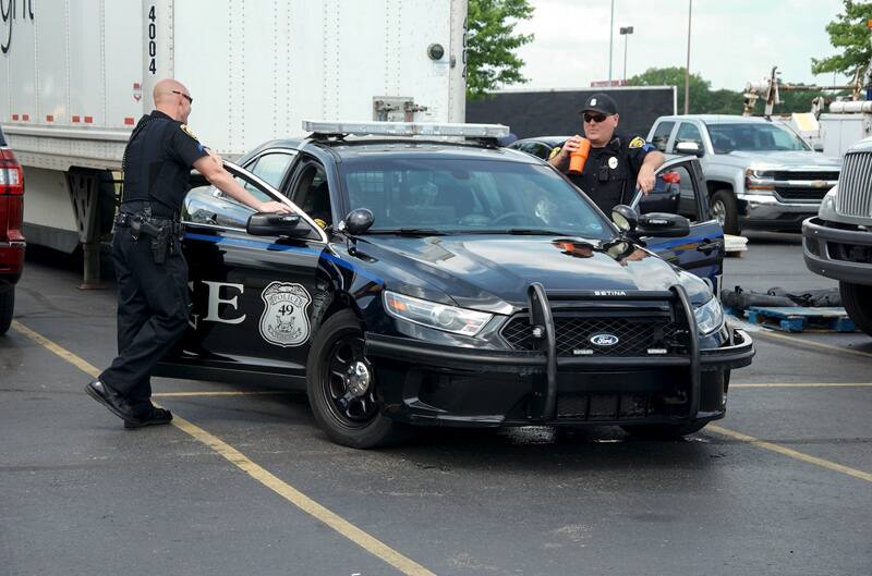 Two police officers standing outside a police car