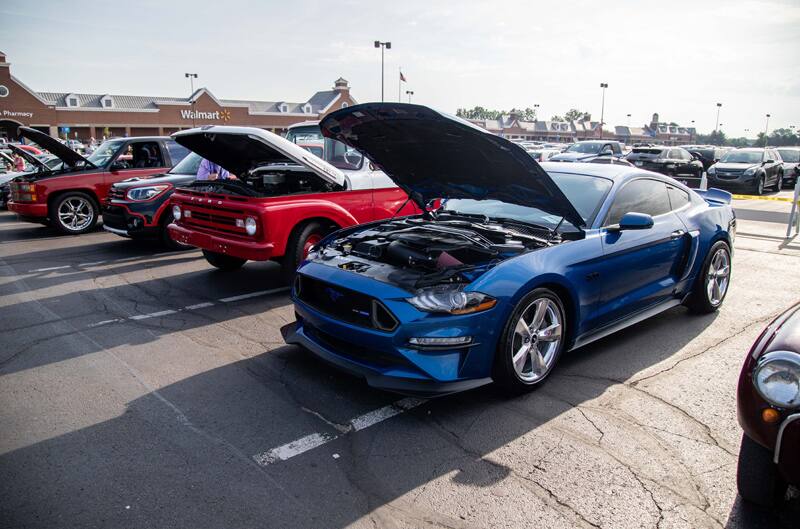 A front side view of a blue Mustang on display in the Walmart parking lot