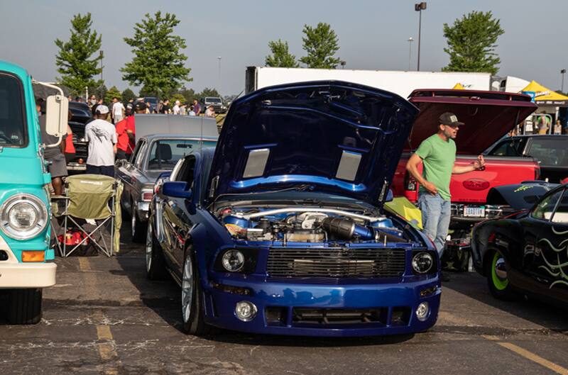 A front end view of a blue Mustang on dislpay with the hood up