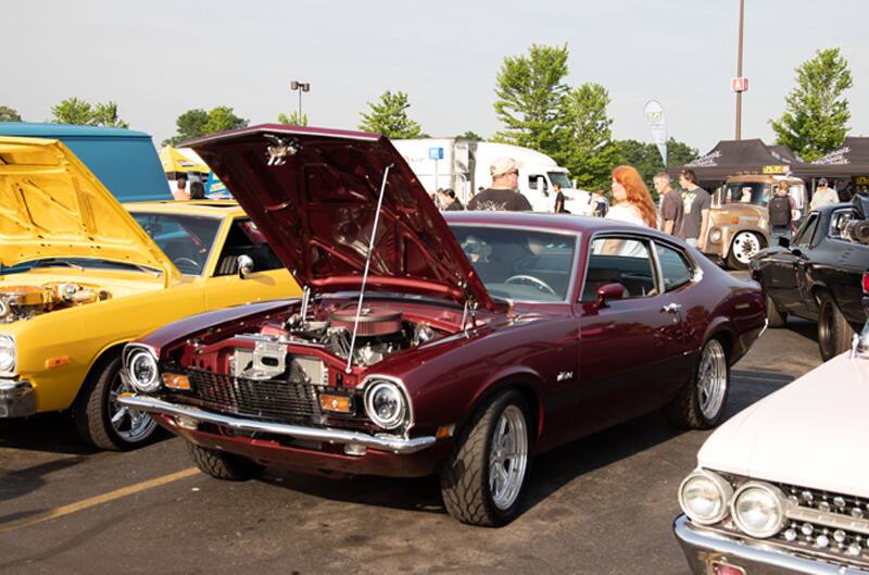 A classic maroon Mustang on display with the hood up