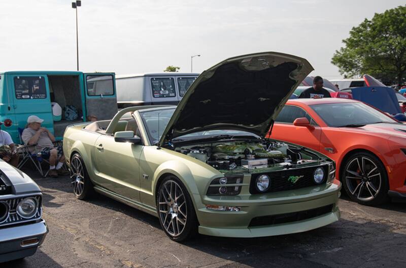 A light green Mustang convertible on display with the hood up