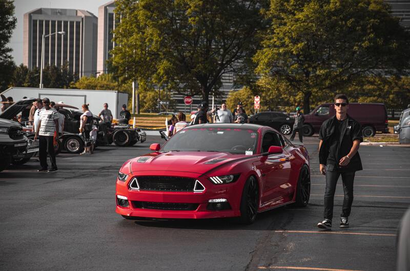 A red Mustang driving down the parking lot