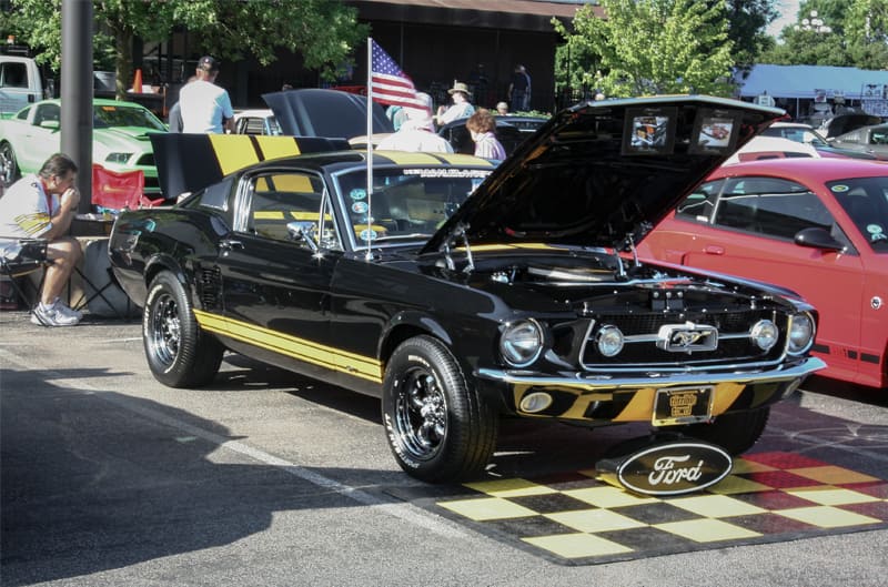 A black and yellow Mustang on display with the hood and trunk open