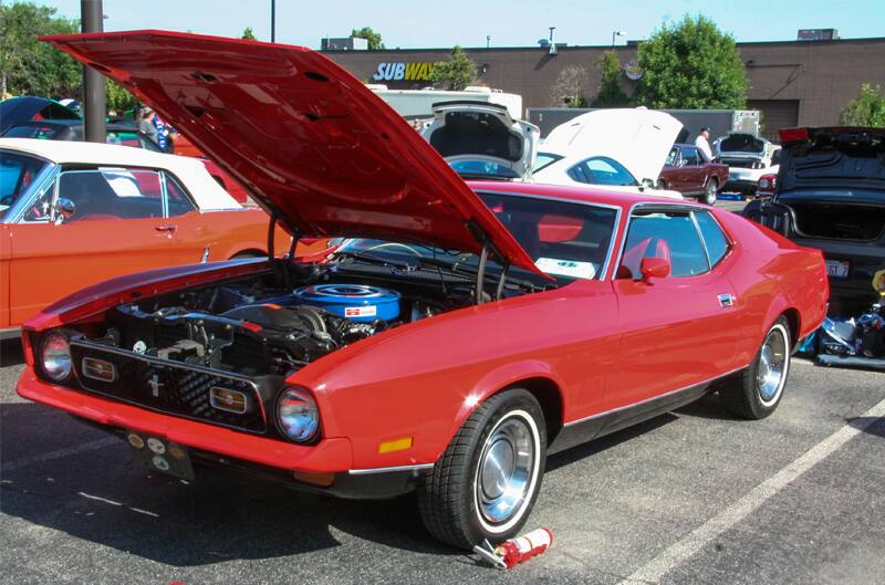 A red Mustang on display with the hood up