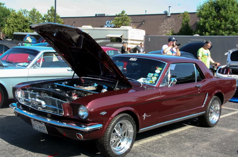 A classic maroon Mustang on display with the hood up