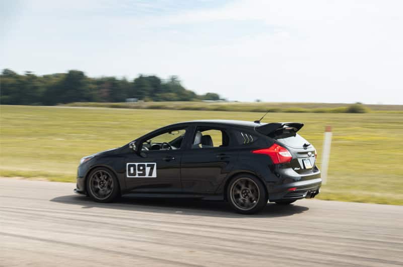A black Ford compact car racing down the track