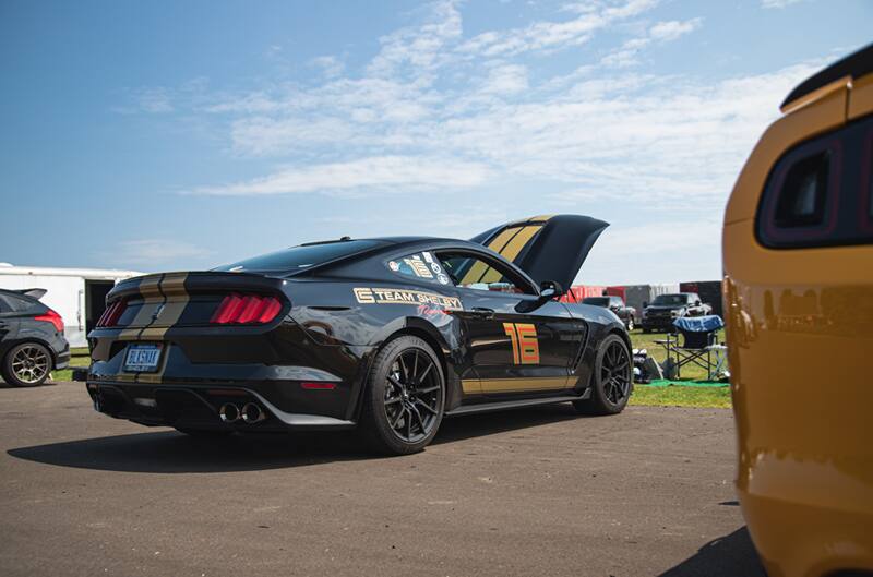 A rear side view of a black Mustang on display with the number 16 on the side