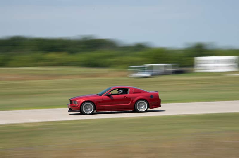 A red Mustang driving down the track