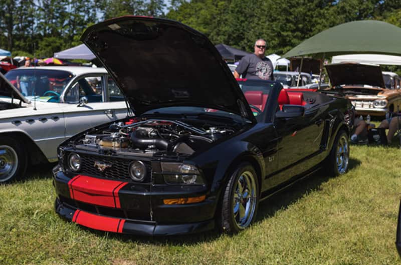 A black and red Mustang on display with the hood up