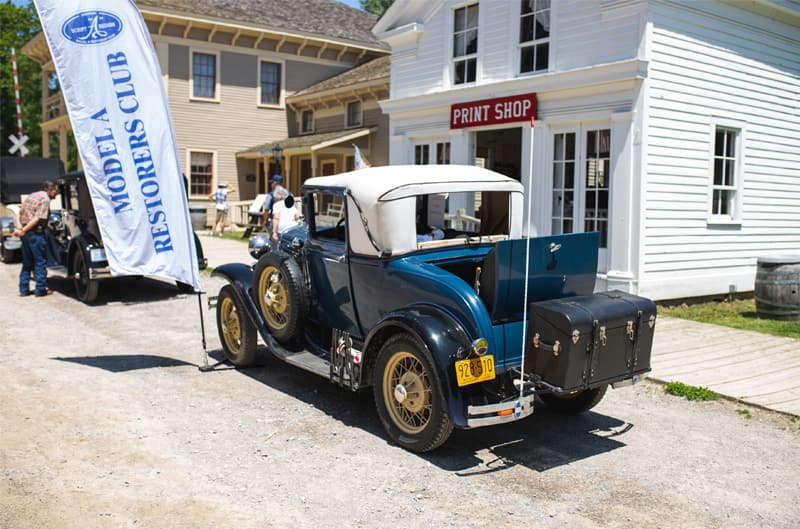 A rear side view of a classic blue vehicle on display