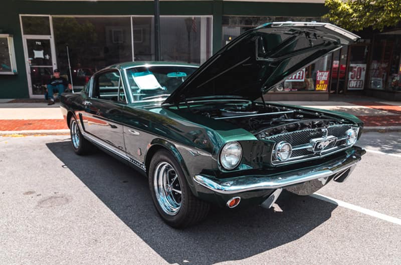 A classic green Mustang on display with the hood up