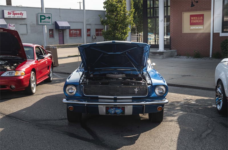 A front end view of a classic blue Mustang on display with the hood up