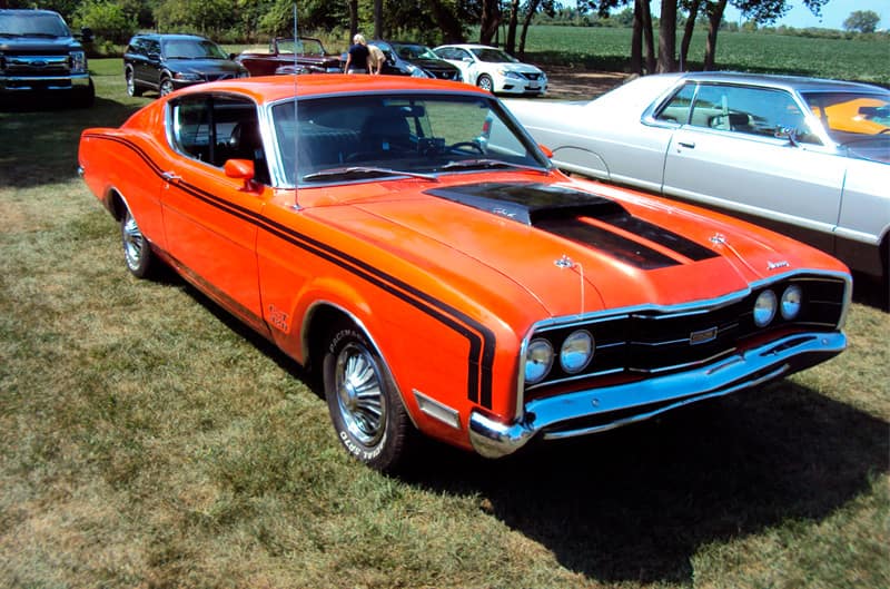 Front profile of a orange Mercury parked on the grass