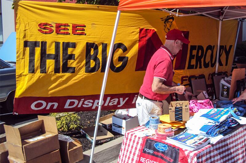 A picnic table of merchandise with a man standing behind it