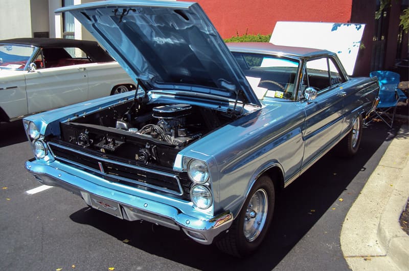 Front of a blue Mercury with hood open in the parking lot