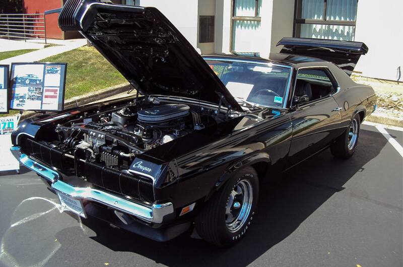 Front of a black Cougar with hood open in the parking lot